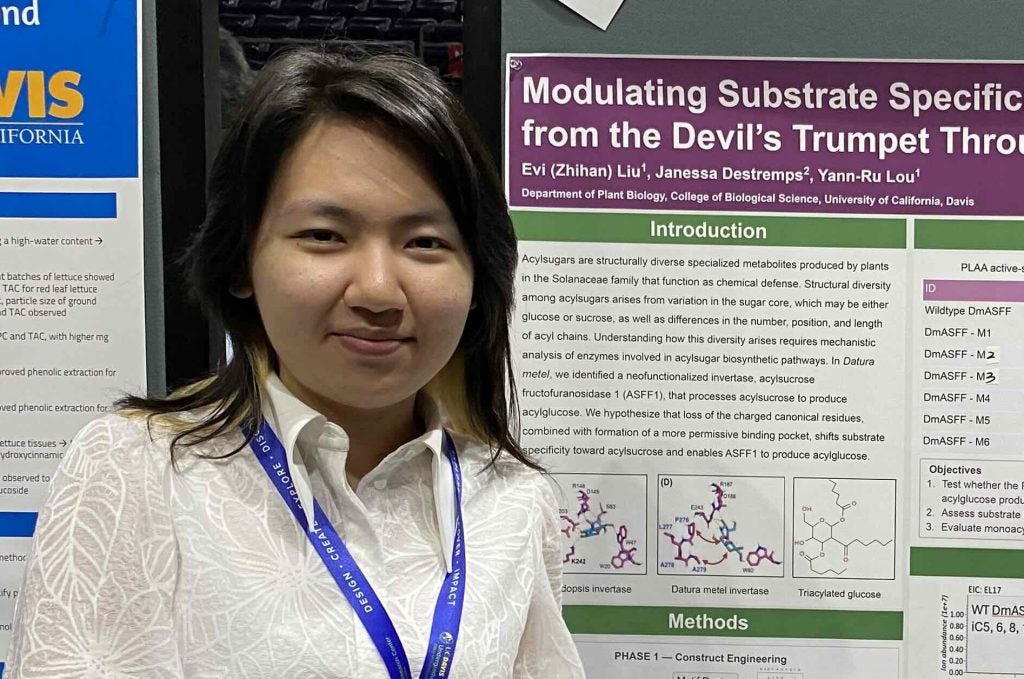Evi smiling in front of her poster.